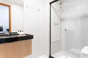 ein weißes Badezimmer mit Dusche und Waschbecken in der Unterkunft Malia Beach Experience Muro Alto Porto de Galinhas por Brevelar in Ipojuca