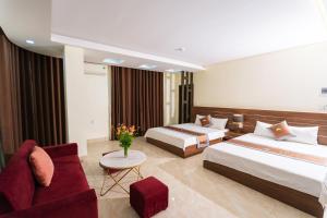 a hotel room with two beds and a couch at Hải Tiến Sunshine Hotel in Mỹ Ðuc
