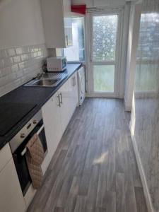 a kitchen with white cabinets and a wooden floor at Four Bedroom House in Gillingham in Gillingham