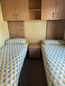 two beds in a small room with wooden cabinets at The Grosvner 61 in Dunoon
