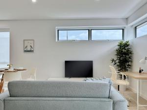 a living room with a couch and a tv at Casa Lumi Walk to Marina & Beach in Shellharbour