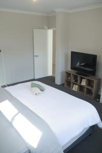 a bedroom with a white bed and a flat screen tv at Home Sweet Perth in Perth