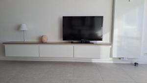 TV de pantalla plana en la parte superior de un centro de entretenimiento blanco en Studio met zeezicht, en Ostende