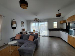 a living room with a gray couch and a kitchen at Les pivoines Notre-Dame-de-Monts in Notre-Dame-de-Monts