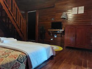 a bedroom with a bed and a tv and wooden walls at Pondok Radnata in Tenganan