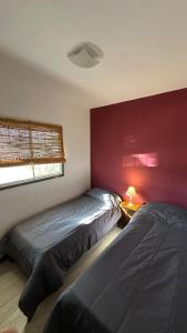 a bedroom with two beds and a red wall at Container Serrano in San Gerónimo