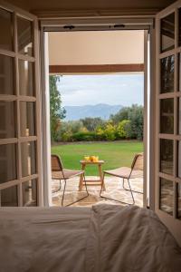 ein Schlafzimmer mit Blick auf eine Terrasse mit Tisch und Stühlen in der Unterkunft Anoixi vacation home with spectacular Evia landscapes in Loukísia