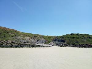 a sandy beach in front of a cliff at Un séjour à la Roulotte in Écault +5 photos