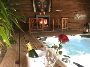 a hot tub with a bottle of champagne and a fireplace at Domaine de Basse Chancelée in Ligré