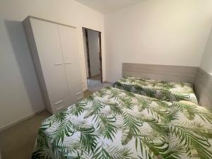 a bedroom with a bed with a green leaf bedspread at Villa Gloria appartamento D02 in Rosolina Mare
