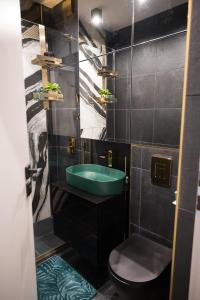 a bathroom with a green sink and a toilet at Луксозен арт апартамент в близост до центъра на града in Sofia +19 photos