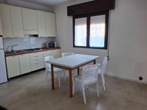 a kitchen with a table and white chairs in a room at Villa Gloria appartamento D01 in Rosolina Mare +13 photos