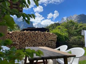 a table and chairs in front of a pile of fire wood at Apartment HasliView in Innertkirchen
