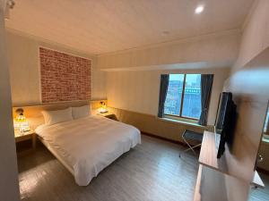 a hotel room with a bed and a television at Chillax Inn 知樂愛河館 in Kaohsiung