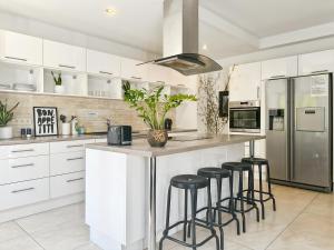 a kitchen with white cabinets and a island with bar stools at Hatton - 650m do plaży ! in Grzybowo