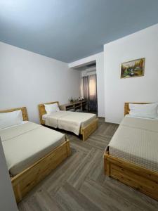 two beds in a room with white walls and wooden floors at The White Villa in Bogovë
