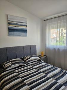 a bed with striped pillows in a bedroom with a window at Apartment Mare Paola in Medulin