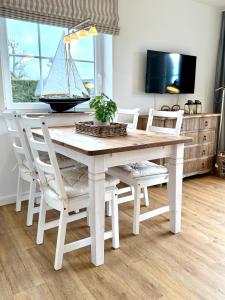 ザンクト・ペーター・オルディングにあるFrida SPO Ferienwohnung Nordsee mit Hundの白いダイニングテーブルと椅子、そしてその上に置かれた帆船