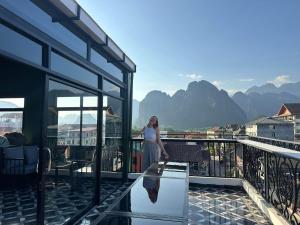 a woman standing on a balcony with a view of mountains at Champa Riverside Hotel in Vang Vieng