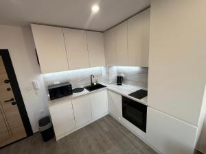 a small kitchen with white cabinets and a sink at Sarafovo Relax Night in Burgas City