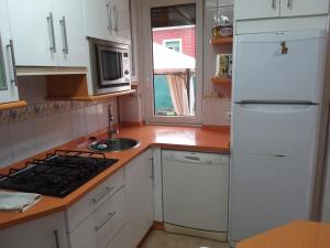 a kitchen with white cabinets and a white refrigerator at Casa Cabarceno Piscina y Barbacoa in Bofetán