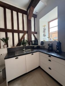 a kitchen with white cabinets and a sink at Maison de charme au cœur de Saint Valéry sur Somme in Saint-Valery-sur-Somme +23 photos