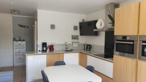 a kitchen with white cabinets and a white table and chairs at Le Gryselis in Gréoux-les-Bains