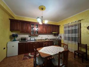 a kitchen with wooden cabinets and a table and a refrigerator at VilaHasa Private Villa in Tërbuf