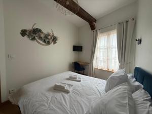 a bedroom with a white bed with two towels on it at Maison de charme au cœur de Saint Valéry sur Somme in Saint-Valery-sur-Somme