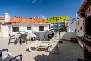 Un patio con una mesa y sillas y una sombrilla. en Azenha Beach House - Sea view with BBQ, en Santa Cruz