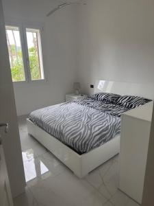 a white bedroom with a zebra print bed with a window at Villa Gioia in Is Molas 