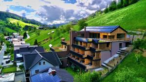 a building with solar panels on the side of a hill at Goldhirsch Aparthotel in Wagrain