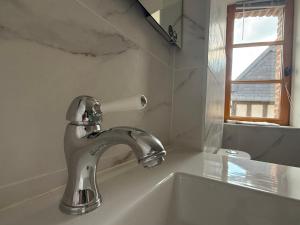 a bathroom sink with a faucet and a window at Maison de charme au cœur de Saint Valéry sur Somme in Saint-Valery-sur-Somme