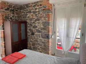Un dormitorio con una pared de ladrillo con una cama y una ventana. en Precioso piso 1 muy cerca de la playa de Salinas, en Piedras Blancas