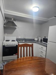 a kitchen with a table and a stove and refrigerator at A space of your own in Rotorua