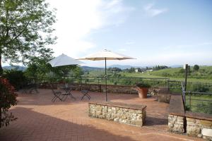 a patio with benches and umbrellas with a view at Agriturismo Bruscola in San Casciano in Val di Pesa