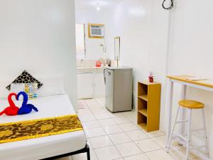 a room with a kitchen with a bed and a stool at Glo's Space Boracay Dmall By JustGoFun in Boracay