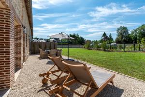 two lawn chairs and an umbrella on a patio at Maisons H Normandie in Cricquebœuf