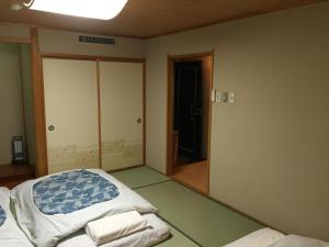 an empty room with a bed and a mirror at Hotel Crown Hills Kitami in Kitami
