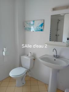 a white bathroom with a toilet and a sink at Gîte de La Ferme de La Cour in Crasville