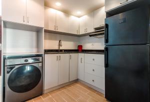 a kitchen with white cabinets and a black refrigerator at Studio with Pool View C106 -Al Saraya Sahl Hasheesh by Peaks in Hurghada