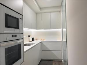 a white kitchen with a sink and a microwave at Villa Aneto - Confort moderno en el corazón de Benasque in Benasque