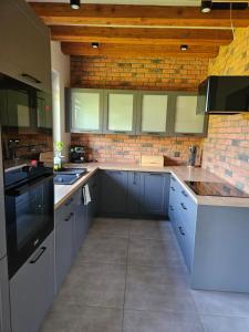 a kitchen with blue cabinets and a brick wall at Siedlisko na Winnicy in Opatów