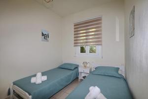 two twin beds in a room with a window at Magnolia House Stafylos in Skopelos Town