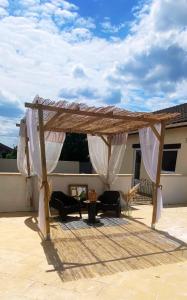 a wooden pergola with white curtains on a patio at Maison de campagne Piscine, jacuzzi 2P Monflanquin in Savignac-sur-Leyze