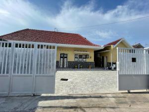 a house with white gates in front of it at D'Dalem Kadipaten Homestay in Yogyakarta