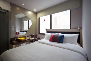 a bedroom with a large white bed and a mirror at Hotel Clover 7 in Singapore