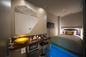 ein Schlafzimmer mit einem Bett, einem Waschbecken und einem Spiegel in der Unterkunft Hotel Clover 7 in Singapur