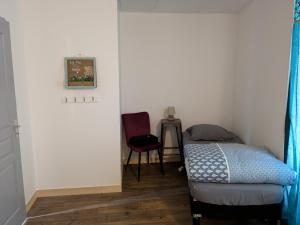 una piccola camera con letto e sedia di Chez Cornélia a Estaing Altre 25 foto