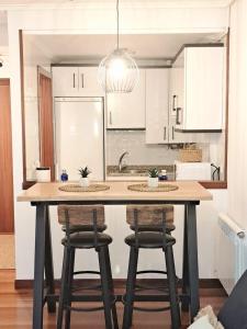 a kitchen with a large wooden table with stools at Pura Vida Apartmento in Ramales de la Victoria